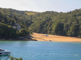 A beach with boats and trees near the water at 4 The Elms in Salcombe