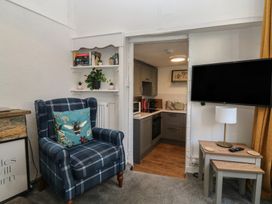 A living room with an armchair and a view of the kitchen at The Cottage in Budleigh Salterton