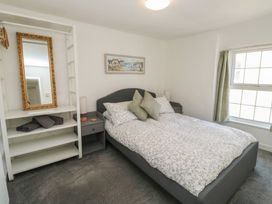 A bedroom with a bed and shelves at The Cottage in Budleigh Salterton