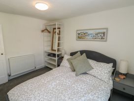 A bedroom with a bed and shelves at The Cottage in Budleigh Salterton