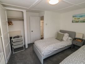 A bedroom with two beds and a wardrobe at The Cottage in Budleigh Salterton