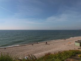 A beach with people walking and a beach hut at The Cottage Budleigh Salterton