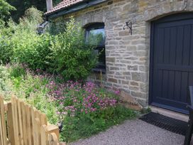 An outdoor area with flowers and a wooden gate at Castle Rag in Parkend