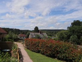 A pathway leading through hedges with houses and trees at Castle Rag in Parkend