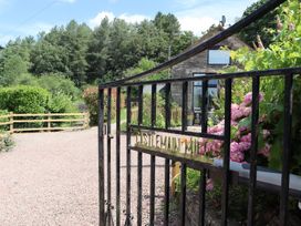 A view of a garden entrance with flowers and a gate at Castle Rag in Parkend