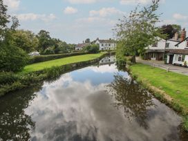 A river reflecting clouds near houses and trees at Tulip in Eardisland