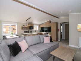 A living room with a sofa and kitchen area at Tulip in Eardisland