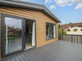 An outdoor deck area with sliding doors and wooden walls at Tulip in Eardisland
