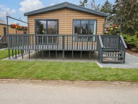 A wooden cabin with a deck and planters at Tulip in Eardisland