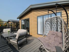 A deck with a hanging chair and table at Tulip in Eardisland