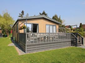 A wooden house with a deck and grassy area at Tulip in Eardisland