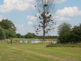 A view of a tree and a pond with a fence at Poppy in Eardisland