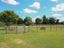 A fenced area with a picnic table and trees at Poppy in Eardisland