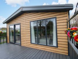 A wooden cabin with large windows and a veranda at Poppy in Eardisland