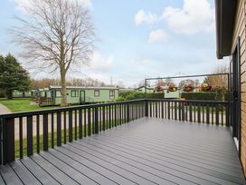 A deck area overlooking holiday homes and trees at Poppy Eardisland