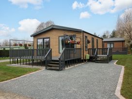 A mobile home with a deck and lawn at Poppy in Eardisland