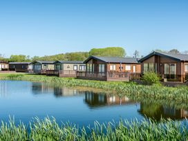 A row of cabins by a lake at Poppy in Eardisland