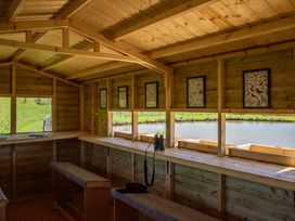 A wooden cabin with tables and benches overlooking a pond at Poppy in Eardisland