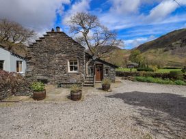 A stone house with flower pots and trees at Beckside Studio in Penrith
