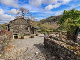 A stone house with trees and a gravel path at Beckside Studio Penrith