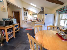 A kitchen with a microwave, sink, stove, and table at Beckside Studio in Penrith