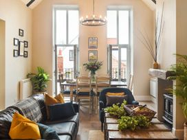 A living room with a dining area and windows at Juniper Cottage