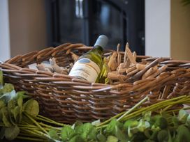 A basket containing a wine bottle and driftwood at Juniper Cottage