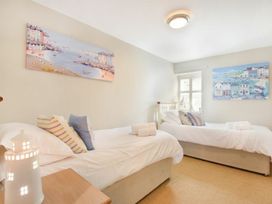 A bedroom with two beds and paintings on the wall at Juniper Cottage