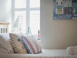 A bedroom with pillows on a bed and sailboat models on a window sill at Juniper Cottage