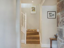 A hallway with stairs and framed pictures at Juniper Cottage