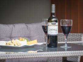 A wine bottle and glasses with cheese and bread on a platter at Juniper Cottage 