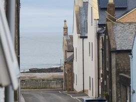 A coastal view with buildings along the road near the sea at Juniper Cottage