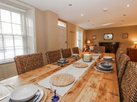 A dining room with a wooden table and wicker chairs at Awelon Y Mor in Aberaeron