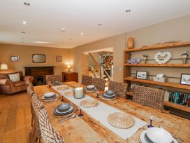 A dining room with a large wooden table and chairs at Awelon Y Mor Aberaeron