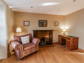 A living room with an armchair and fireplace at Awelon Y Mor in Aberaeron