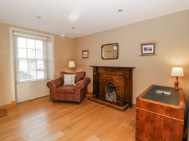 A living room with a fireplace and armchair at Awelon Y Mor in Aberaeron