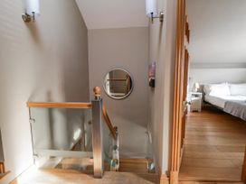 A staircase leading to a bedroom with a bed and lamp at Awelon Y Mor in Aberaeron
