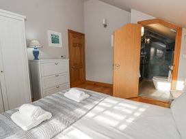 A bedroom with a bed and a bathroom door at Awelon Y Mor Aberaeron