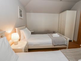 A bedroom with two beds and a wardrobe at Awelon Y Mor in Aberaeron