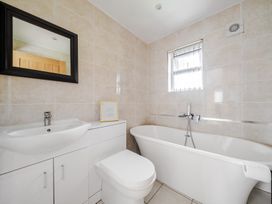 A bathroom with a sink, toilet, bathtub, and mirror at Poker Lodge Near Brigg