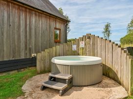 An outdoor area with a hot tub and wooden fence at Poker Lodge Near Brigg