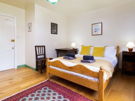 A bedroom with a bed, chair, table, and lamps at Oakdene in Keswick