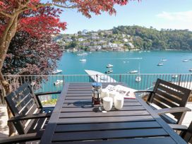 An outdoor seating area with a table and chairs overlooking water at Galvayne in Dartmouth