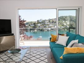 A living room with a sofa and a coffee table with a view of the water at Galvayne in Dartmouth