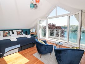 A bedroom with a bed and chairs overlooking the water at Galvayne in Dartmouth