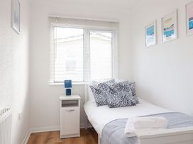 A bedroom with a bed, nightstand, lamp and window at Ms Merryn 37 St. Cadocs