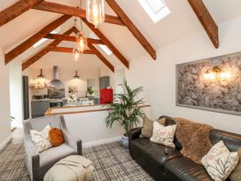 A living room with a sofa and chair leading to an open kitchen at The Old Byre in Falmouth