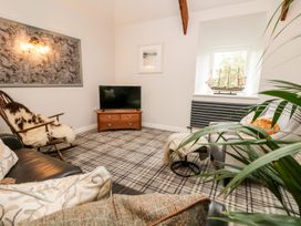A living room with a television and rocking chair at The Old Byre in Falmouth