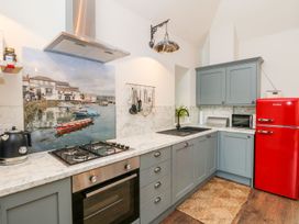 A kitchen with cabinets, stove, sink, and refrigerator at The Old Byre in Falmouth