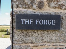 A sign on a stone wall stating The Forge in Falmouth